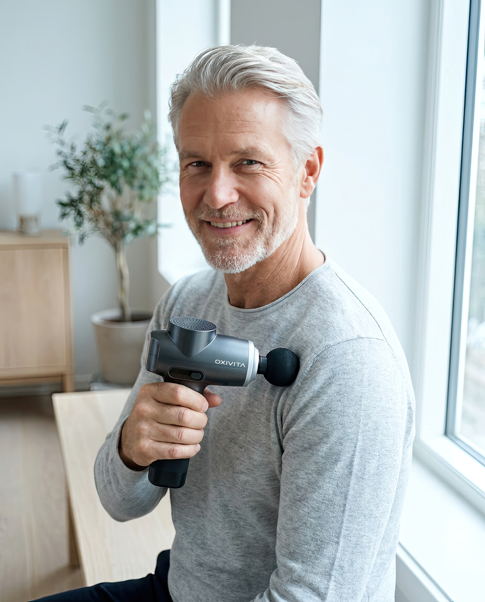 Leende man håller OXIVITA CORE M1 massagepistol